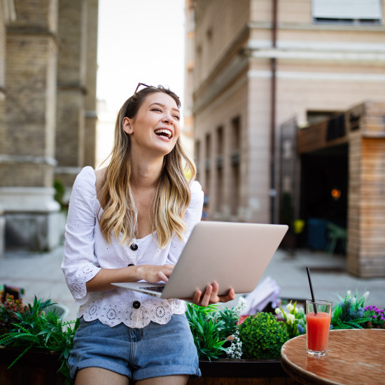 Excited woman reading good news on line in a laptop outdoor
